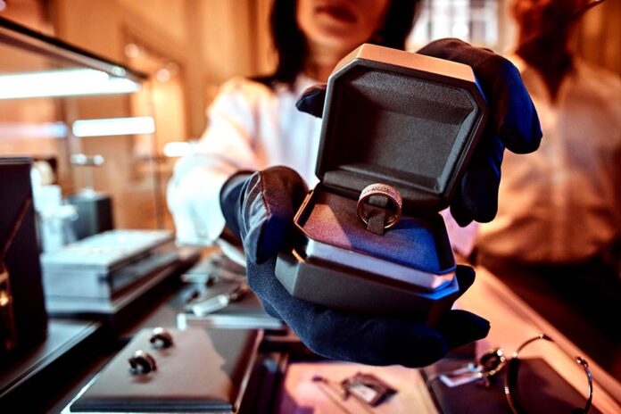 Woman assistant shows the exclusive gold ring in the jewelry store