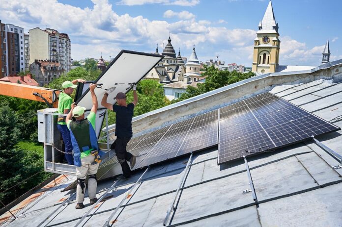 Workers building solar panel system on roof of house. Installers carrying photovoltaic solar module