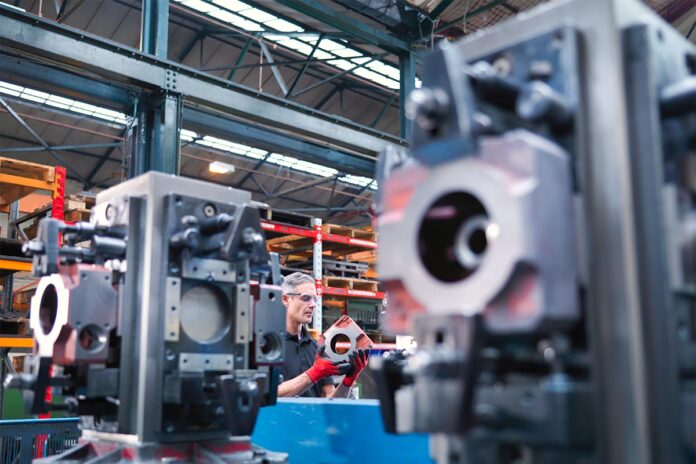 Engineer inspecting parts on automatic lathe in engineering factory