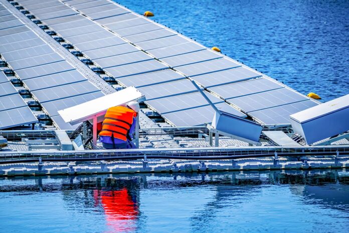 Local worker working at floating solar panels platform on the water of solar cell power plant.