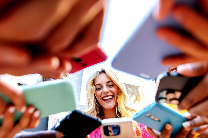 Young group of people having fun using mobile phones at city street