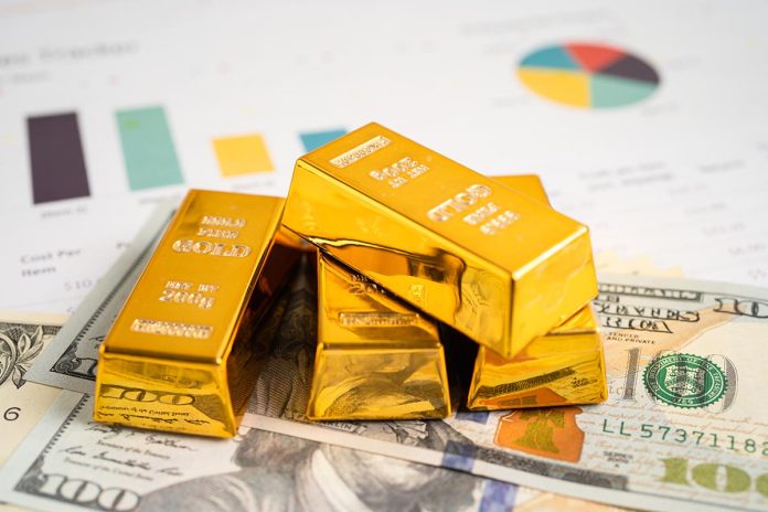 Gold bar in shopping cart on US dollar banknotes money and graph