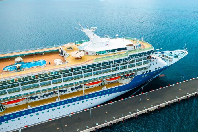 Aerial view of a luxury cruise ship or linear with a swimming pool on the roof moored in marina.