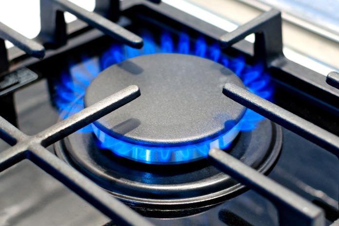 Gas burner burns with a blue flame on the stove under the protec