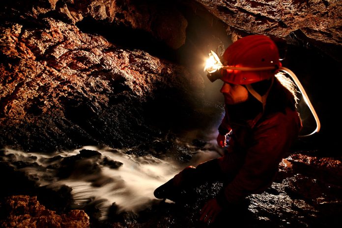 spelunker-exploring-underground-river-in-a-cave-2023