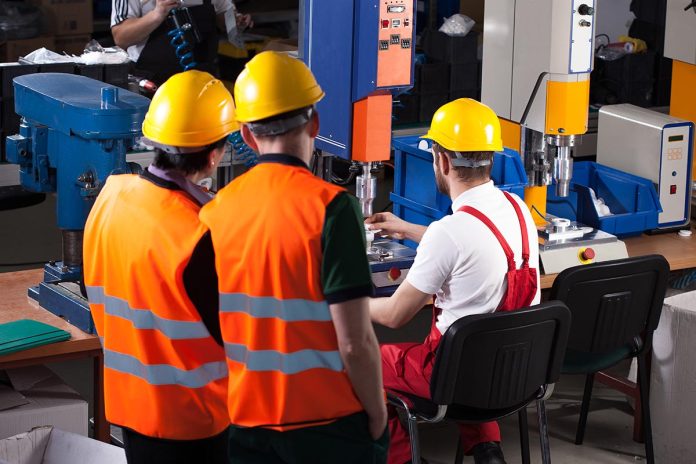 Three,Labourers,In,Safety,Helmets,Are,Working,In,Factory