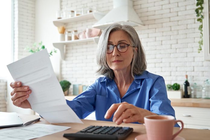 Senior,Mature,Business,Woman,Holding,Paper,Bill,Using,Calculator,,Old