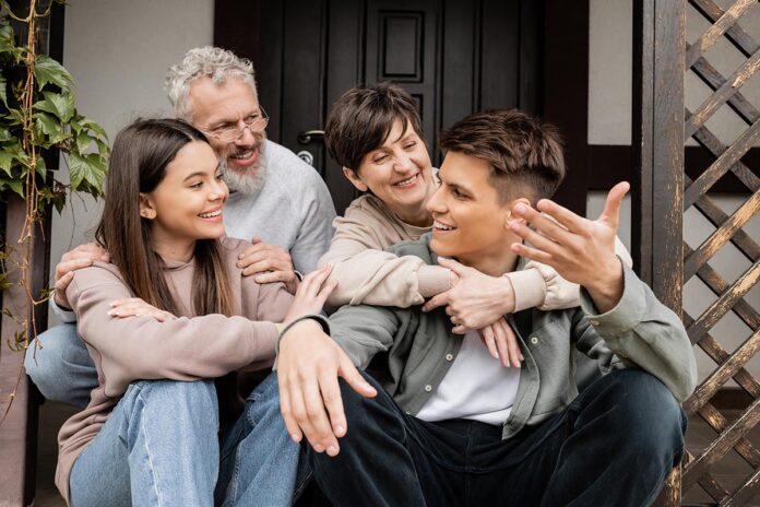 Smiling young man talking to family and sister while sitting on