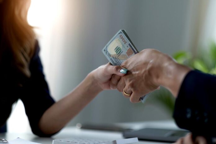 A female lawyer or business legal consultant receives a bribe or tribute from her client in the office. Corruption concept. cropped and close-up image