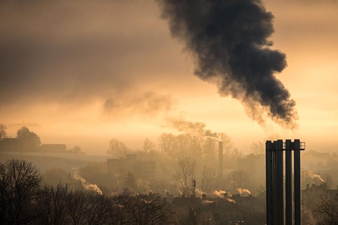 Factory emitting smoke and polluting the air on the sunset