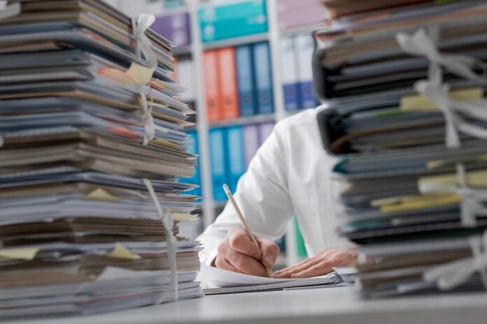 Business,Executive,Working,In,The,Office,And,Piles,Of,Paperwork,