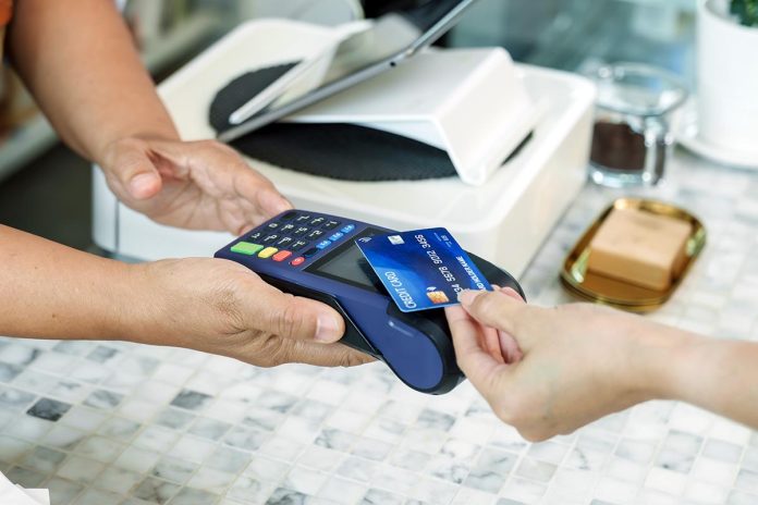 Closeup,Of,Terminal,Held,At,Coffee,Shop,Counter,While,Customer