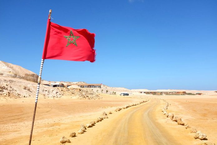 Desert,Road,With,Moroccan,Flag,In,Western,Sahara,Leading,To