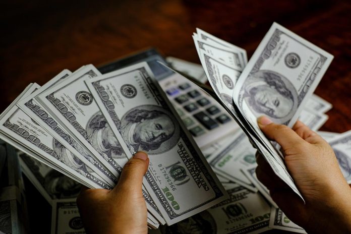 Businessmen women counting money on a stack of 100 US dollars ba