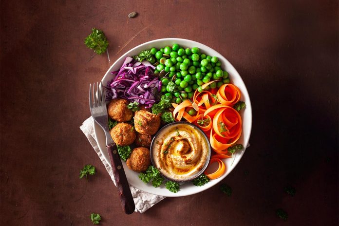 healthy vegan lunch bowl with falafel hummus carrot ribbons cabb