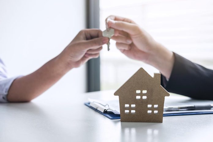 Estate agent giving house keys to client after signing agreement