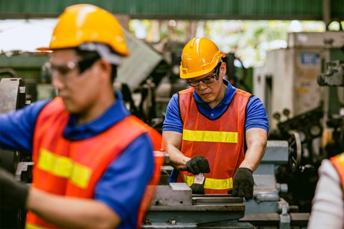 Asian expert technician engineer male focus detail working precision manual cut lathe milling metal production in heavy industry