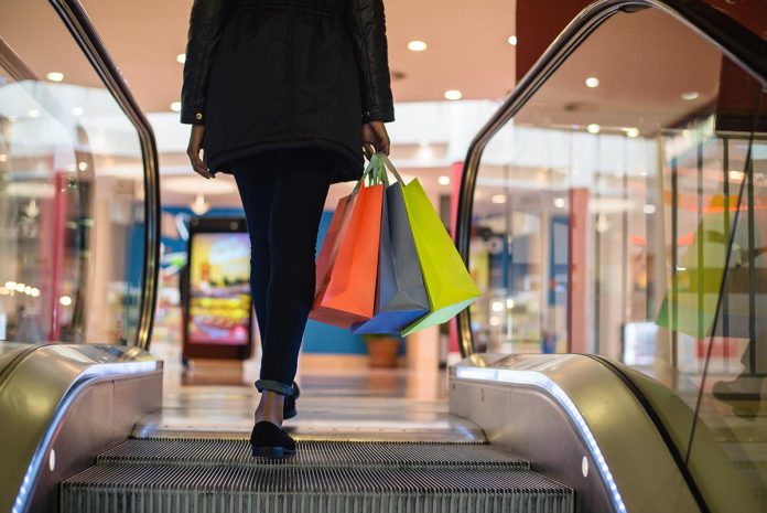 Woman legs with colourful shopping bags on the escalator in a shopping mall